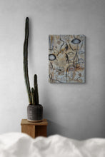 Abstract painting on a wall with a cactus plant on a wooden stand.