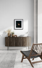 Modern interior with a wooden sideboard, chair, and decorative items against a white wall.